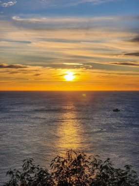 Güneş Promthep Burnu 'ndan (Phuket, Tayland) batıyor. Durgun denizin üzerindeki gökyüzünü botlarla turuncuya boyuyor. 