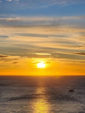 Güneş Promthep Burnu 'ndan (Phuket, Tayland) batıyor. Durgun denizin üzerindeki gökyüzünü botlarla turuncuya boyuyor. 