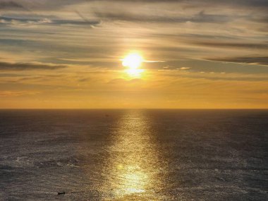 Güneş Promthep Burnu 'ndan (Phuket, Tayland) batıyor. Durgun denizin üzerindeki gökyüzünü botlarla turuncuya boyuyor. 