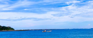 Aydınlık bir günde mavi okyanusun ortasında küçük bir tekne..