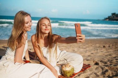 Bir grup genç kadın, mutlu anlarını kutlamak için manzaralı bir plajda selfie çekiyorlar. Yüksek Kalite Fotoğraf