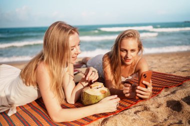 En iyi iki arkadaş okyanusun kenarında dinleniyor, taze hindistan cevizi suyu yudumluyor ve birlikte huzurlu bir kumsal gününün tadını çıkarıyorlar..