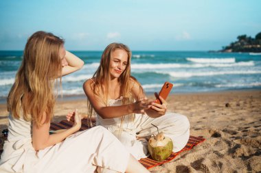 Arkadaşlar sahilde neşeli selfie çekerler tropikal havanın tadını çıkarırlar ve sıcak güneşin altında gülümserler. Yüksek Kalite Fotoğraf