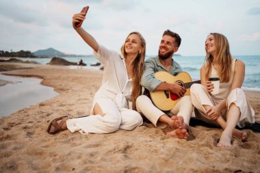 Üç yakın arkadaş plajda unutulmaz ve eğlenceli anlar yakalar, neşeli müzik ve neşe dolu kahkahalarla.