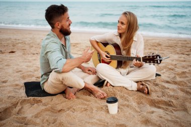 Genç ve güzel bir çift kumsalda huzurlu bir gündoğumu anının tadını çıkarıyor. Kız, birlikte gülümseyip rahatlarken gitar çalıyor. Aşkın, müziğin ve yaz özgürlüğünün özünü yakalıyor..