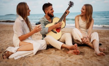 Neşeli bir grup genç arkadaş yaz güneşinin altında kumlu sahilde dinleniyor. Bir adam gitar çalarken diğerleri dinler, güler ve kaygısız atmosferin tadını çıkarır. Bağlantı, müzik ve gençliğin özgün anlarını yakalar.