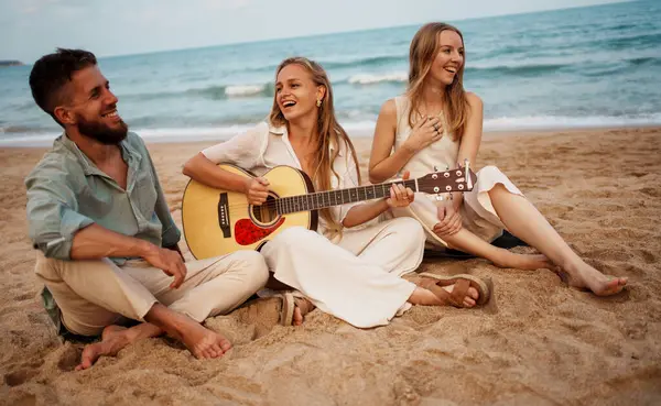 Bir grup genç arkadaş plajda rahat bir yaz gününün tadını çıkarıyor. Akustik gitar çalıyorlar, gülümsüyorlar ve birlikte deniz kenarında takılıyorlar. Doğal ve tasasız bir ortamda pozitif titreşimler paylaşıyorlar..
