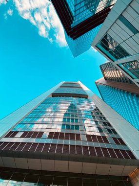 Geniş gökyüzünü yansıtan, modern mimariyi gösteren, dinamik görünümlü, gökdelenler.