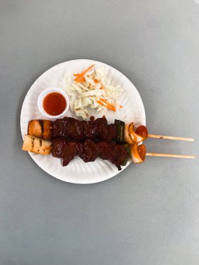 Soğan, ananas ve sebzeli Tayland biftek şişleri kağıt tabakta sos ve salata ile servis edilir. Sokak yemekleri, kültür, tat, gelenek.