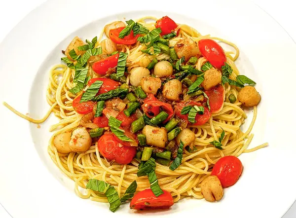 Bay Scallops, Cherry Domatesleri ve kuşkonmaz ile süslenmiş spagetti..
