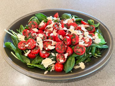 Tıraşlı Parmesan peynirli vişneli domates ve bebek ıspanak salatası.