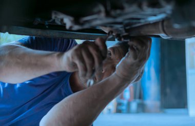 Latin tamirci bir arabanın şasesini ayarlıyor.
