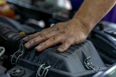 Tamirat sırasında tamircinin kirli eli arabanın motorunda.