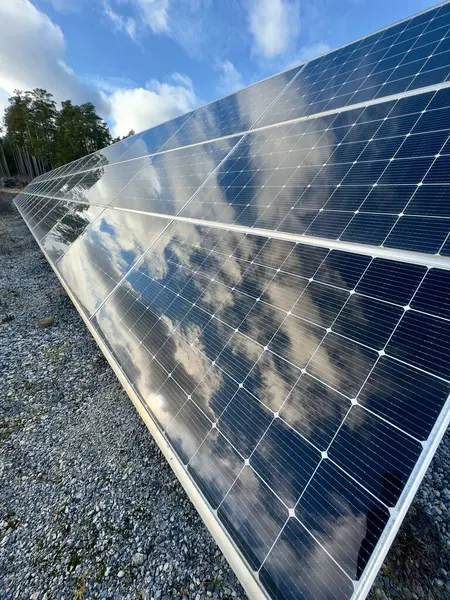 Mavi gökyüzünü ve bulutları yansıtan güneş panellerine yakın çekim. Temiz enerji, sürdürülebilirlik ve çevre dostu teknoloji. Yeşil enerji, yenilenebilir kaynaklar ve çevresel kavramlar için ideal.