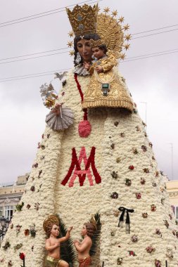 Bebek İsa 'yı tutan Bakire Meryem' in çiçekli heykeli kalabalık ve binalarla çevrili geleneksel bir dini festival sırasında halka açık bir meydanda sergileniyor..