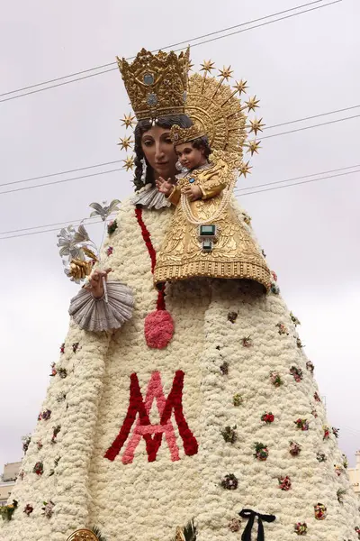 Bebek İsa 'yı tutan Bakire Meryem' in çiçekli heykeli kalabalık ve binalarla çevrili geleneksel bir dini festival sırasında halka açık bir meydanda sergileniyor..