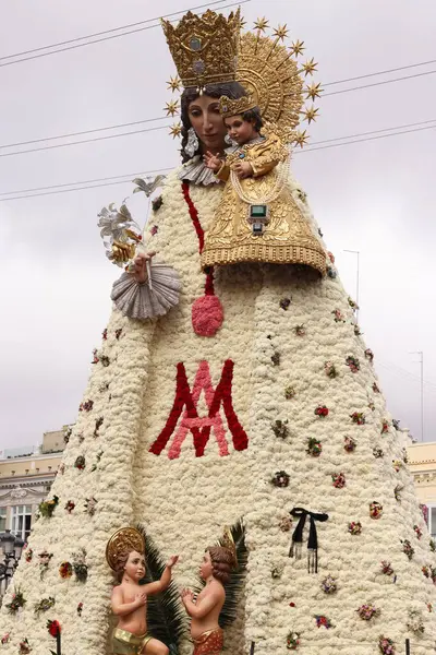 Bebek İsa 'yı tutan Bakire Meryem' in çiçekli heykeli kalabalık ve binalarla çevrili geleneksel bir dini festival sırasında halka açık bir meydanda sergileniyor..
