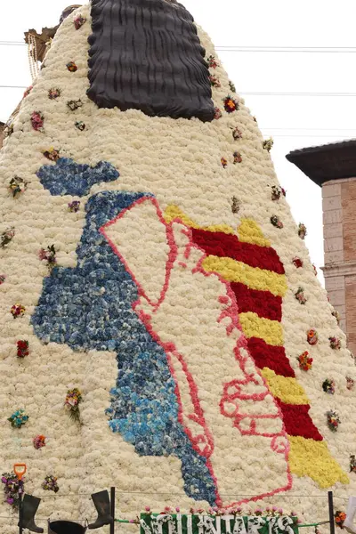 Bebek İsa 'yı tutan Bakire Meryem' in çiçekli heykeli kalabalık ve binalarla çevrili geleneksel bir dini festival sırasında halka açık bir meydanda sergileniyor..