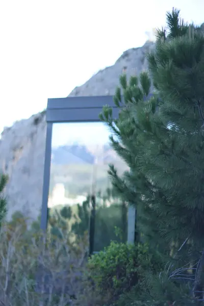 Fotoğraf, parçalı bulutlu bir gökyüzünün altında engebeli, kayalık tepeleri olan dağlık bir manzarayı gösteriyor. Dağlar ise dipdiri bir bitki (ler) ve hoş kokulu ağaçlarla kaplıdır. Ön planda..