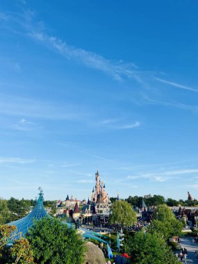 Disneyland Paris 'in geniş bir görüntüsü. Ortasında Uyuyan Güzel Kalesi var. Etrafı yeşillik ve açık mavi gökyüzü ile çevrili..