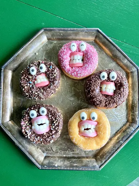 Klasik gümüş tepside dizilmiş şeker gözlü ve dişli yaratıcı Cadılar Bayramı temalı çörekler. Eğlenceli ve ürkütücü tatlı mevsimsel yemek içeriği ve parti görselleri için mükemmel..