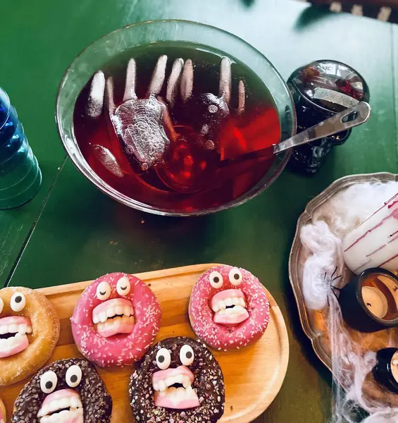 Cadılar Bayramı temalı oyuncaklar canavar suratlı çörekler, buzlu kırmızı punç ve çeşitli ürkütücü şekerler de dahil. Bayram temalı yemek içeriği ya da parti ilhamı için parlak ve eğlenceli kurulum ideali.