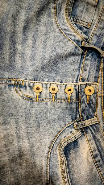 Metal düğmeli kot pantolonlara yakın çekim, ayrıntılı dikişler ve cepler.