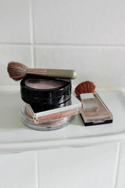 Beyaz seramik bir rafta beyaz seramik zemin üzerinde allık ve allık fırçalı kutular.