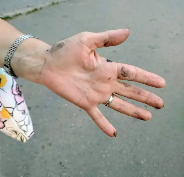 Siyah dondurma yedikten sonra siyah lekeli bir kadın eli. Gümüş bir yüzük ve metal bir saat bileziğiyle bir kadının elinin yakın çekimi, içinde çiçekler olan bir çanta parçası var. Kirli bir kadının eli..