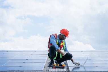 Fabrikanın çatısındaki güneş panellerini inceleyen mühendis doğal yenilenebilir enerji kullanıyor..
