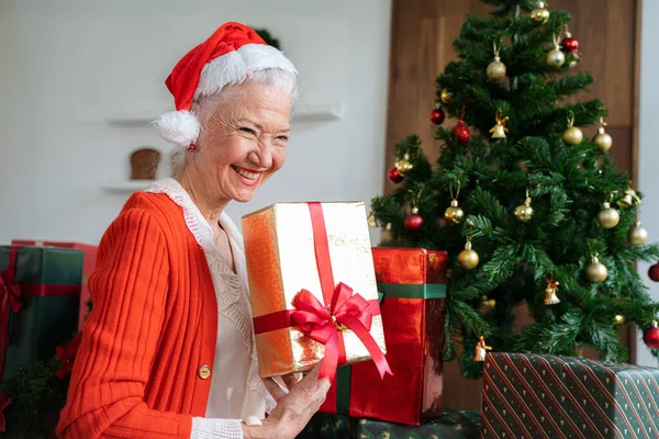 집에서 크리스마스 선물을 나이든 여성에게 미소짓는 — 스톡 사진