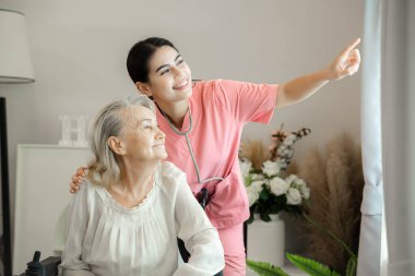 Dost canlısı hemşire yaşlı bir bayanı destekliyor, birlikte huzurlu bir anın tadını çıkarıyor..