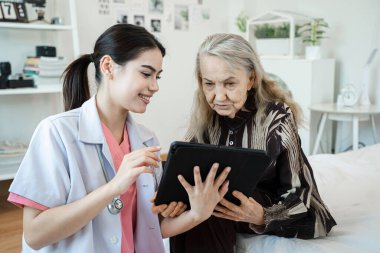 Gülümseyen kadın bakıcı yaşlı büyükanneme sağlık kontrolünde rehabilitasyon merkezinde yardım ediyor..