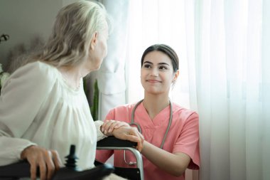 Genç kadın doktor huzurevinde kıdemli hastaya dokunuyor, empati kuruyor, psikolojik yardım kavramı geliştiriyor..