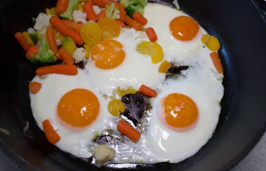 Çırpılmış yumurta ve sebze, siyah bir tavada.