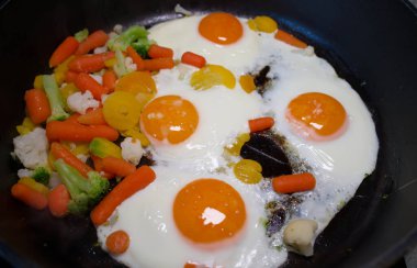 Çırpılmış yumurta ve sebze, siyah bir tavada.