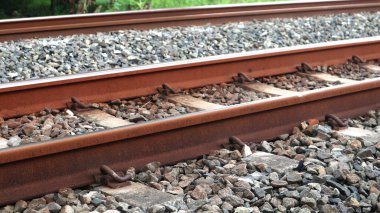 Demiryolu raylarının, paslı metal rayların ve çakıl taşından yatakların yakın görüntüsü. Bu resim demiryolu altyapısının ham dokusu ve endüstriyel yapısını, taşımacılık, seyahat veya endüstriyel temalı projeler için idealini yakalar.