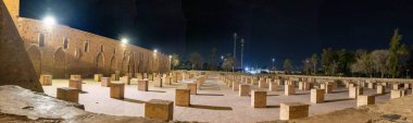 Bir Kuzey Afrika ülkesindeki tarihi bir binanın kalıntılarının gece görüşü. Spot ışıklarıyla aydınlatılan antik tuğla duvarlar ve yapının kemerleri görülebilir durumda. Görüntü, bir avlunun veya iç alanın kalıntılarını gösteriyor.