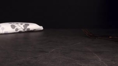 Bir tiramisu keki siyah eldiven giyen bir el mankeni tarafından nazikçe siyah bir tabağa yerleştirilir. Koyu mermer arka plan, altın çatal bıçak takımı ve bir peçete zarafet ekler. Tatlı görselleri için dikey stok video.