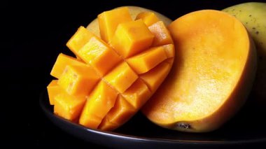 Siyah tabakta 3 mango açılı, soldan sağa kayıyor, bir kirpi stili, güçlü yansıma, koyu siyah zemin