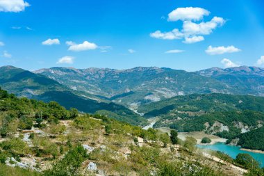 Arnavutluk 'ta, büyük mavi bir gökyüzü ve Tiran yakınlarındaki bazı bulutlarla dağlık bir manzaranın geniş açılı görüntüsü.