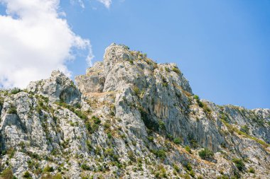 Mavi gökyüzünün altında, güneşin altındaki büyük kayalık dağ..