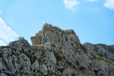 Mavi gökyüzünün altında, güneşin altındaki büyük kayalık dağ..