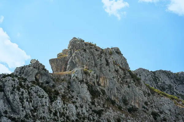 Mavi gökyüzünün altında, güneşin altındaki büyük kayalık dağ..