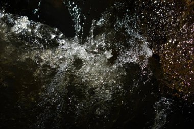 Güneş ışığı hareket eden suyu yansıtır, parlak, parıltılı röflelerden oluşan dinamik bir şablon yaratır. Yüzey, hafif bir ışık ve gölge etkileşimiyle dalgalı bir doku sergiliyor.. 