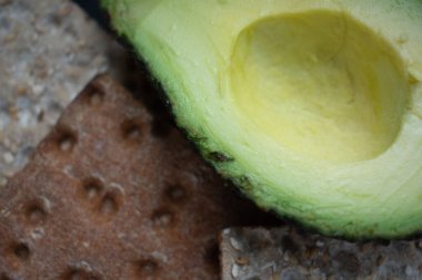 Koyu bir arka planda cips yanında yarım bir avokado, basit ve sağlıklı bir atıştırmalık tazeliği ve doğal iyiliği akla getiriyor. Gıda blogları için ideal sağlıklı yeme promosyonları, ya da malzeme vitrinleri