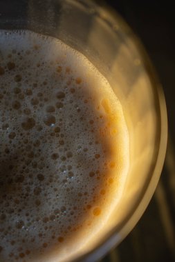 Bu yakın planda köpüklü altın danslar, latte 'yi ima ediyor. Yanardöner kabarcıklar ışığı yakalıyor, canlı ve davetkar bir doku yaratıyor. İçecek reklamları veya soyut enerji kavramları için mükemmel