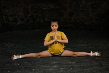 İç huzuru ve dengeyi bul. Bu görüntü gençliğin dinginliğini yakalar ve yoga pozuna odaklanır. Sağlık, farkındalık ve çocukların etkinlik temaları için ideal