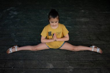 İç huzuru ve dengeyi bul. Bu görüntü gençliğin dinginliğini yakalar ve yoga pozuna odaklanır. Sağlık, farkındalık ve çocukların etkinlik temaları için ideal