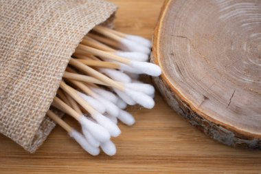  Kırsal bir çuval bezinden ahşap bir yüzeye dökülen doğal bambu pamuk örnekleri. Daha yeşil bir rutin için sürdürülebilir seçenekleri benimse.